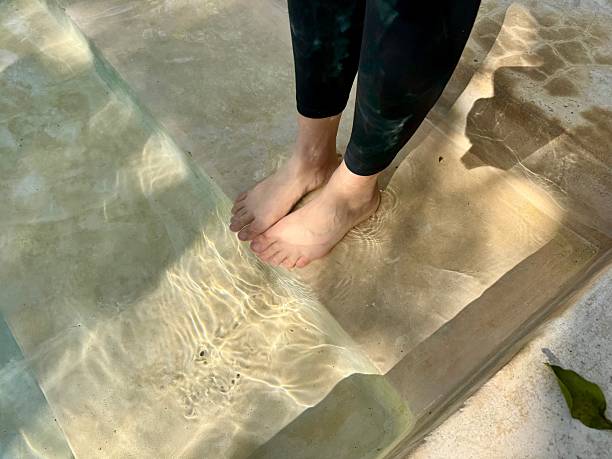 Woman in black leggings cooling her feet in a concrete pool with steps at a boutique hotel in Valladolid, Yucatan, Mexico