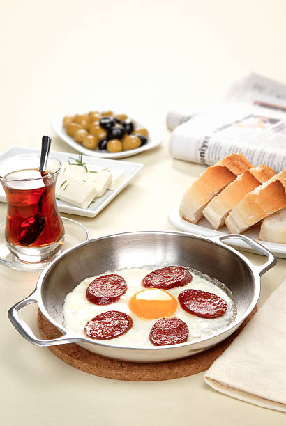 Traditional turkish breakfast with fried egg and sucuk, served with olives, cheese, bread and tea