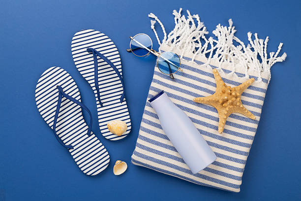 istock Beach towel with summer accessories on color background, top view 2216566080
