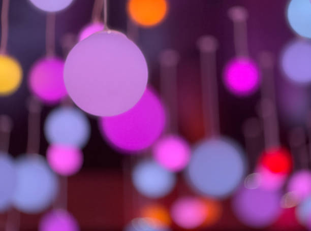 An abstract defocused image showing glowing orbs suspended in the air with vibrant pink, purple, and blue hues. Ideal for modern designs, creative concepts or festive visuals.