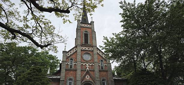 istock Front view of a classic red brick church framed by trees in serene springtime 2216579693