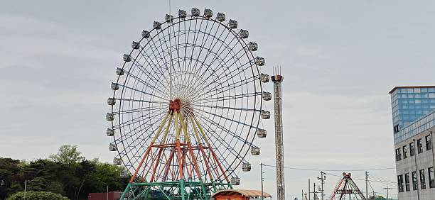 istock Large Ferris Wheel and Drop Tower Ride at Amusement Park on Cloudy Day 2216579916