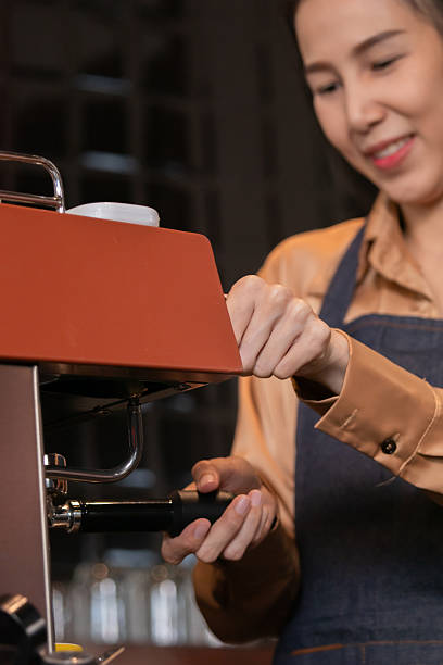 istock Young attractive Asian barista female using professional coffee machine making hot espresso and pouring coffee to mug in cozy cafe, small businesses start up for young people lifestyle concept 2216593901