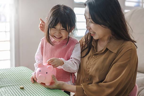 istock Parent and Child Engaged in Saving Activity with Piggy Bank 2216599375