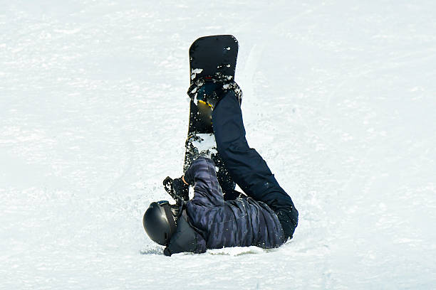 istock Close up Young man snowboarder falls into soft slushy snow while snowboarding on snowy ski slope. Man beginner snowboarder crashes towards camera while making snowboard turn on slope at snowy mountain 2216602468
