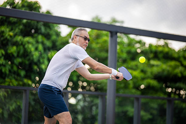 istock Precision and Experience: Mature Player Hitting a Backhand Shot in Outdoor Pickleball 2216604359