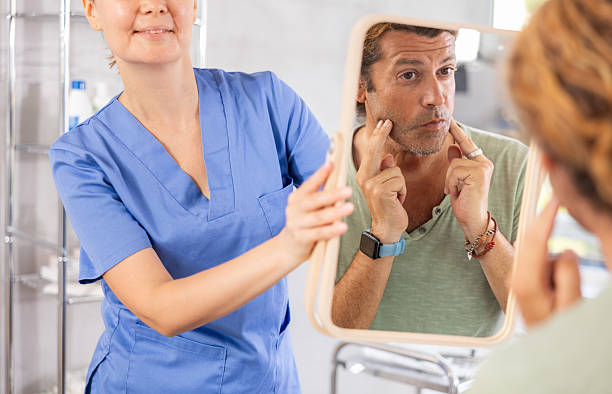 Man scrutinizing his own reflection in mirror held by female cosmetologist