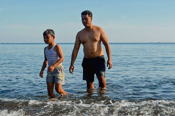 A bonding moment as the father and young boy walk out of the sea together.