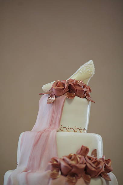 istock Elegant three-tier wedding cake with decorative roses and shoe topper 2216607548