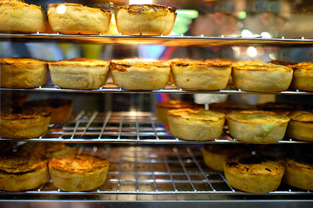 A display case filled with golden savory pies, freshly baked and arranged neatly under warm lighting, evokes comfort and culinary delight.