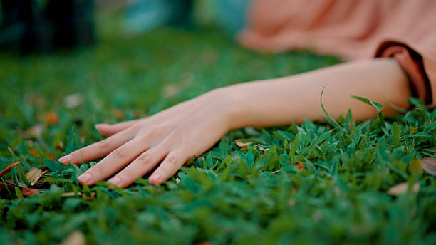 istock Young Asian woman touching grass while relaxing on the ground in a public park. 2216610161