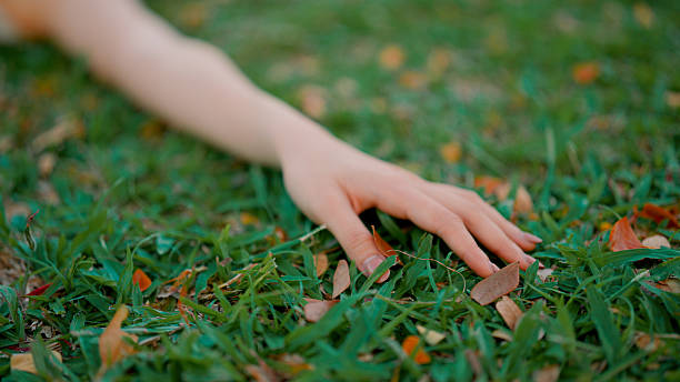 istock Young Asian woman touching grass while relaxing on the ground in a public park. 2216610162