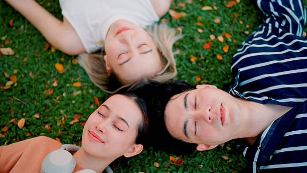 istock Three young Asian friends lying down on grass together as they meet after working hours. 2216610234