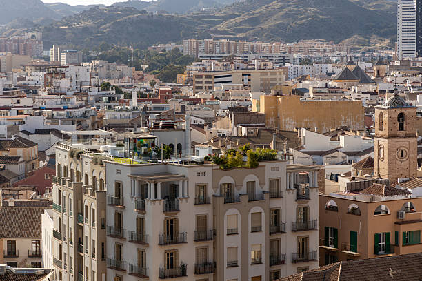 Malaga at sunset. Urban skyline view captures rooftops and buildings bathed in summer sunlight, showcasing vibrant city life and diverse architectural styles