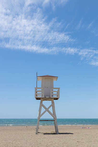 istock Lifeguard tower stands tall on sandy beach under clear blue sky, overlooking tranquil ocean waves and inviting summer atmosphere 2216611021