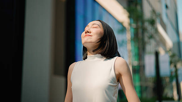 istock Young Asian woman feeling refreshed while taking in fresh air outside office building. 2216612113