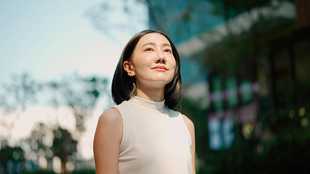istock Young Asian woman feeling refreshed while taking in fresh air outside office building. 2216612117