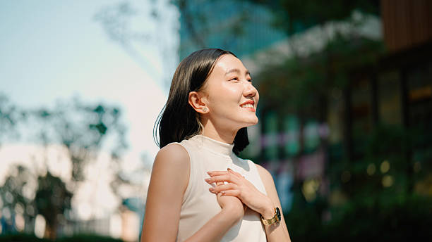 istock Young Asian woman feeling refreshed while taking in fresh air outside office building. 2216612120