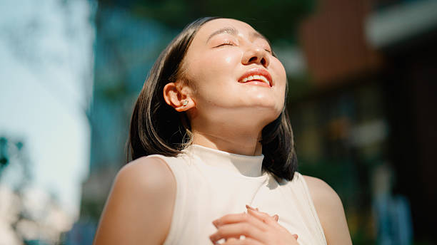 istock Young Asian woman feeling refreshed while taking in fresh air outside office building. 2216612128
