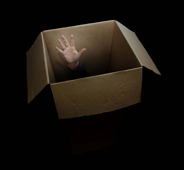 istock A man's hand raised up in a cardboard box, on black background 2216614201