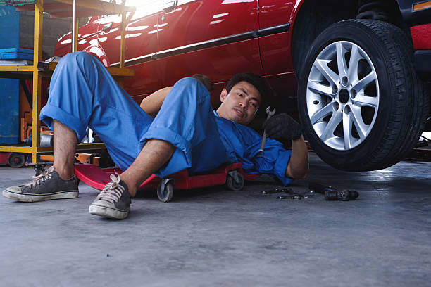 istock Mechanic man using slide board and checking the car suspension in the garage 2216617162
