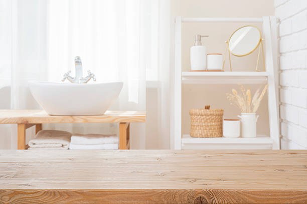 istock Empty wooden texture table top for product showing on blurred curtained bathroom window interior, sink and shelf 2216617332