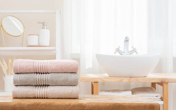 istock Stack of folded soft bath towels on table against blurred bathroom interior background with copy space 2216617346