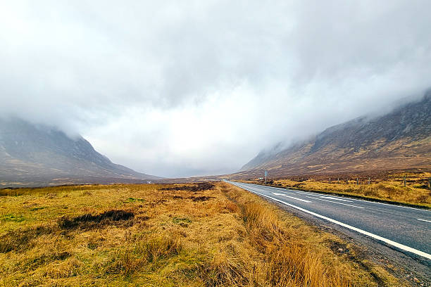 istock Misty Highland Landscape with Roadway through Rolling Hills and Dramatic Sky 2216625244