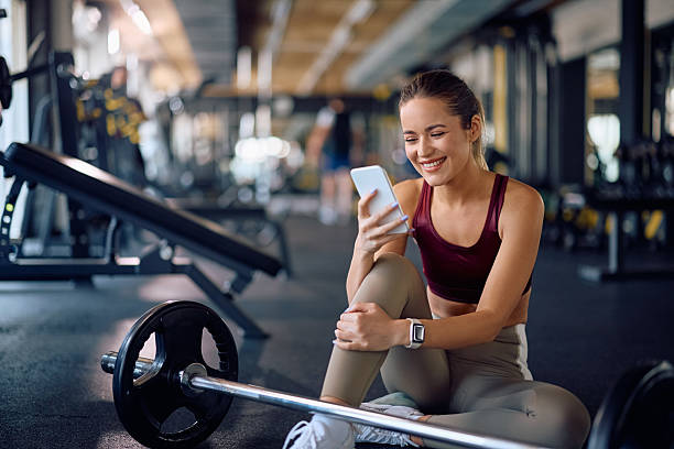 istock Happy athletic woman texting on smart phone while taking a break during strength training in a gym. 2216625526