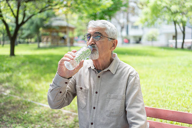 istock Senior Man Sitting In Park And Drinking Water 2216626447
