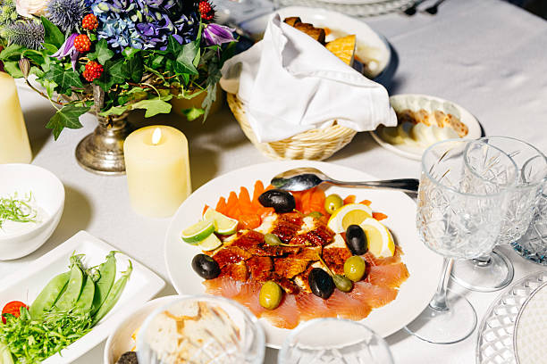 Elegant banquet table featuring a gourmet plate of smoked fish, olives, lemon slices, and fresh garnishes, ideal for events.
