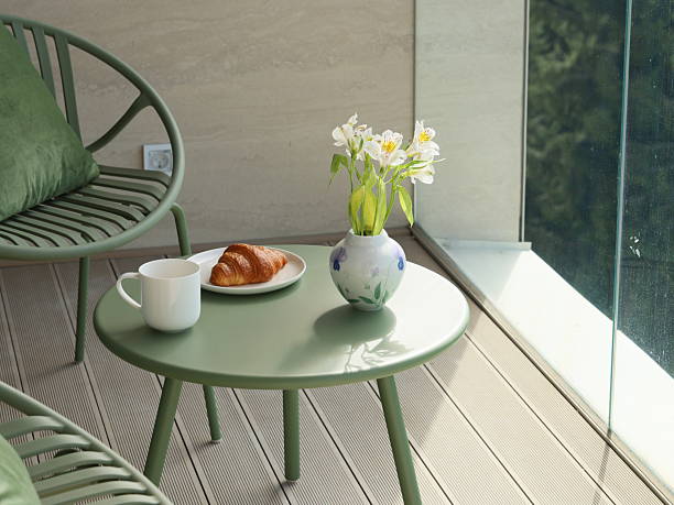 balcony or terrace with two wicker chairs and a potted plant, overlooking a mountainous landscape.