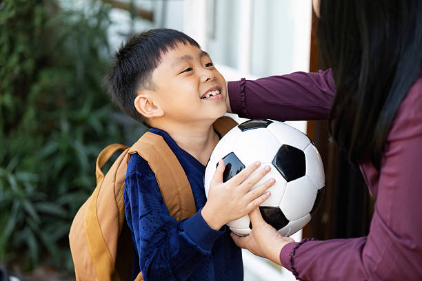 istock Back to School and Soccer Excitement. A young boy with a backpack and soccer ball, smiling as he prepares for school. 2216632529