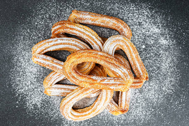 A heap of freshly fried churros is placed on a cooling tray, ready to be sold
