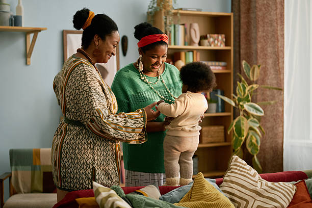 istock Two Smiling Black Women Holding Child while Baby Standing on Couch 2216640688