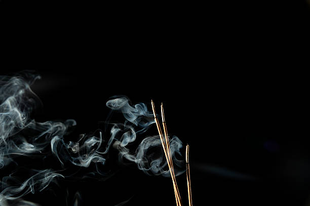 istock Three burning incense sticks with smoke on a black background. 2216642456