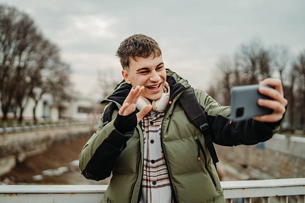 istock Young adult caucasian man student smile using smartphone to talk or send messages sms 2216643705