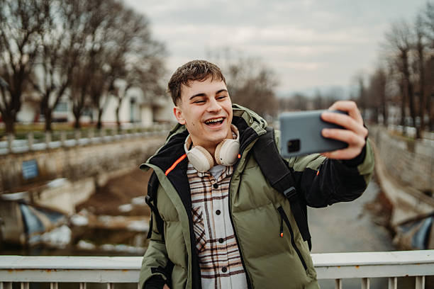 istock Young adult caucasian man student smile using smartphone to talk or send messages sms 2216643712