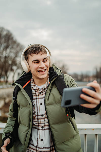 istock Young adult caucasian man student smile using smartphone to talk or send messages sms 2216643713