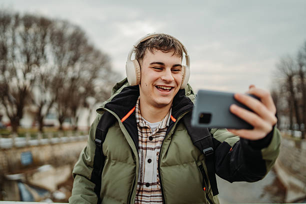 istock Young adult caucasian man student smile using smartphone to talk or send messages sms 2216643714