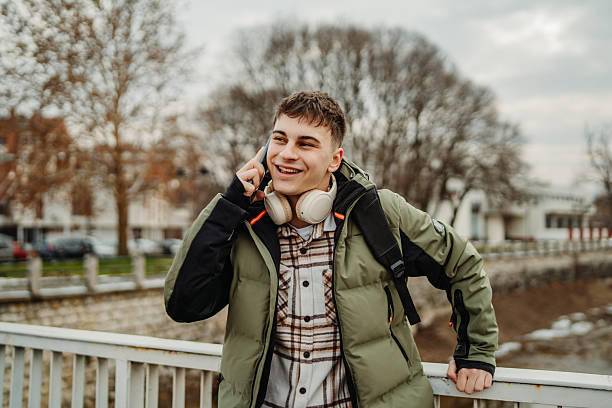 istock Young adult caucasian man student smile using smartphone to talk or send messages sms 2216643729