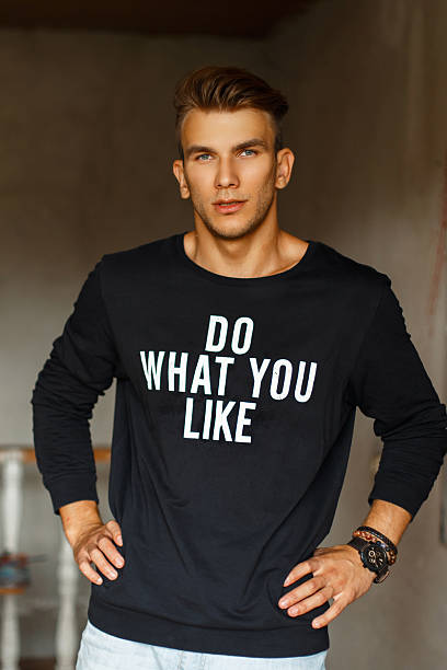 istock Stylish handsome young male artist in a black pullover with words standing in the studio 2216646116