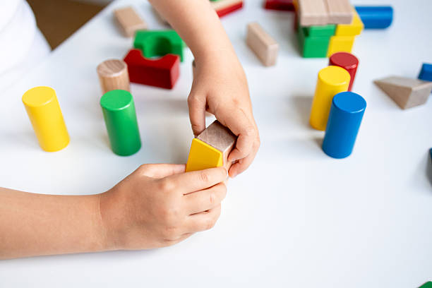 istock Child playing with colorful wooden blocks on white table 2216646475