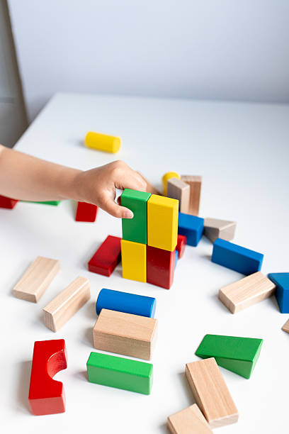 istock Child playing with colorful wooden blocks on a white table 2216646480
