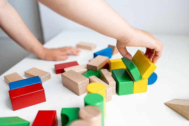 istock Child playing with colorful wooden blocks on a white table 2216646483