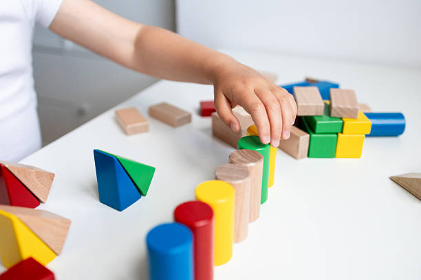 istock Child playing with colorful geometric blocks on white table 2216646484