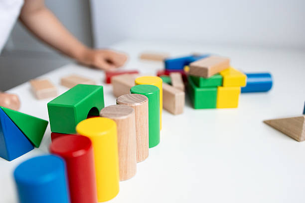 istock Colorful wooden blocks on white table with child hand in background 2216646489