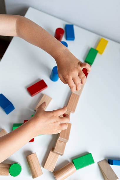 istock Child playing with colorful wooden blocks on white table 2216646490