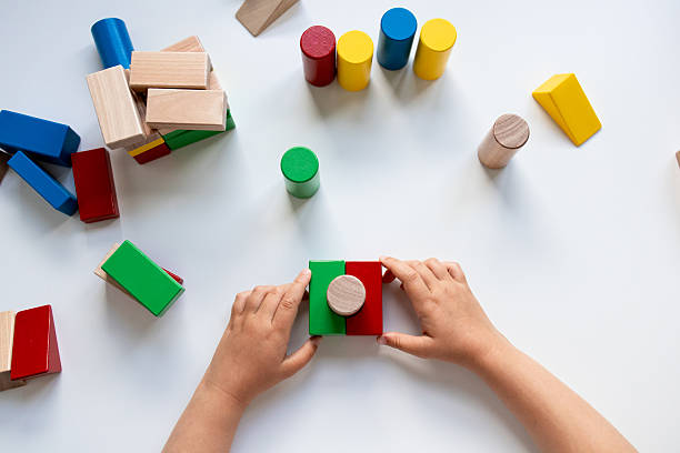 istock Child hands playing with colorful wooden blocks on white surface 2216646736