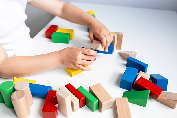 istock Child playing with colorful wooden blocks on white table 2216646742
